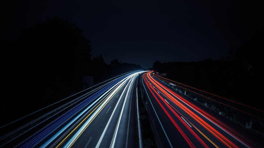 An image of car passing on a highway at night.